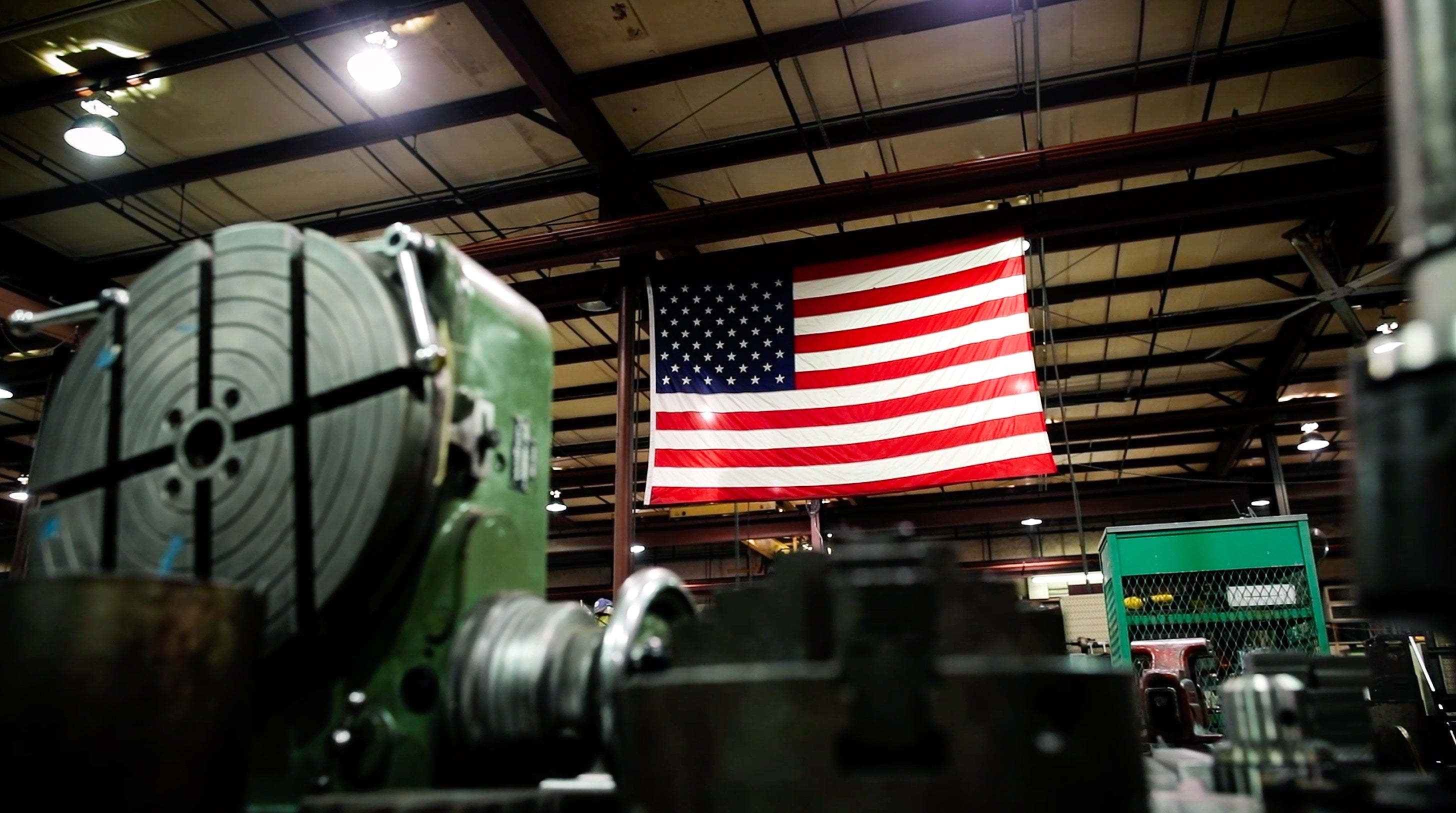 American flag hanging from the ceiling of Wall Control's warehouse with industrial equipment.