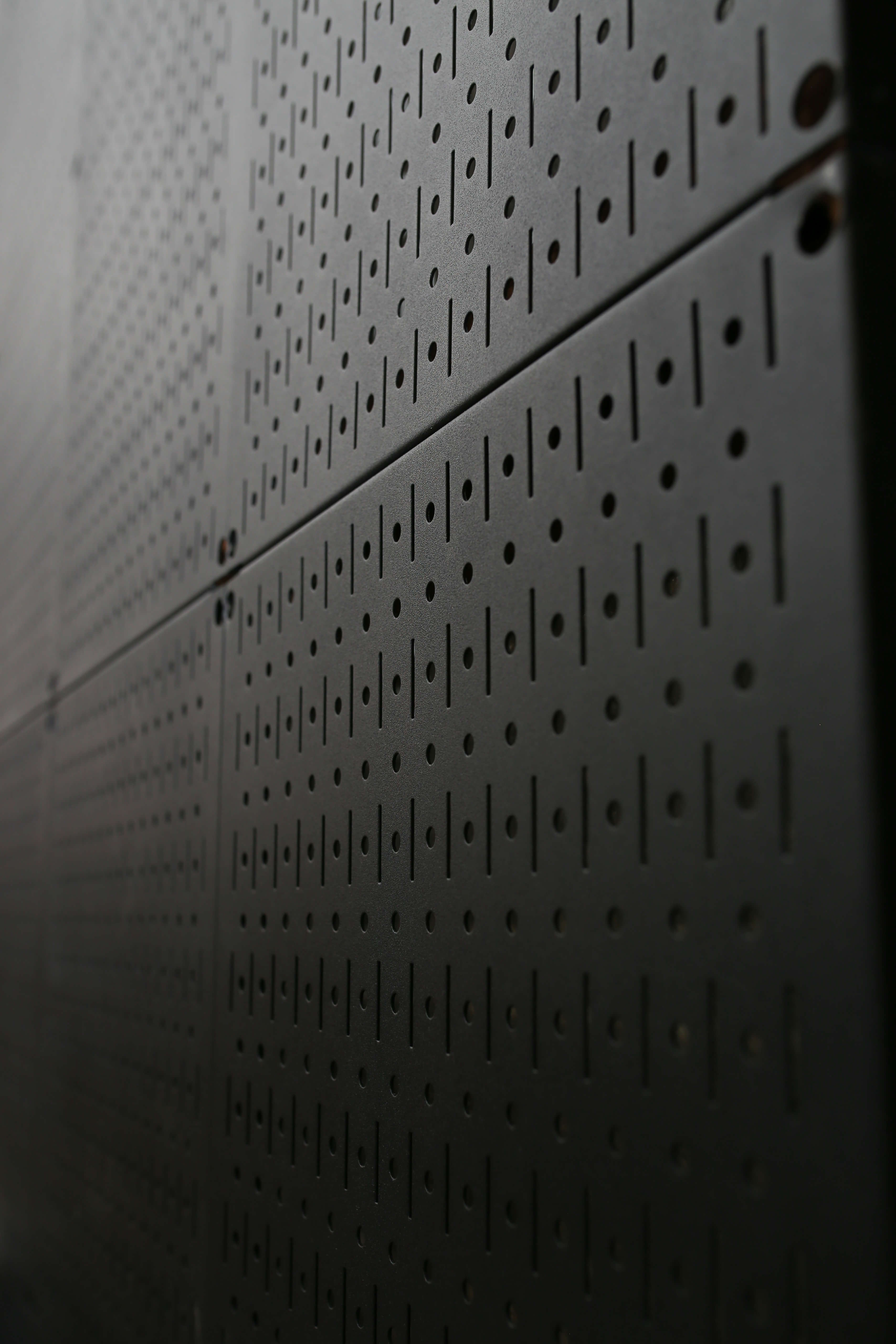 Close-up of a metallic pegboard panel with a grid pattern