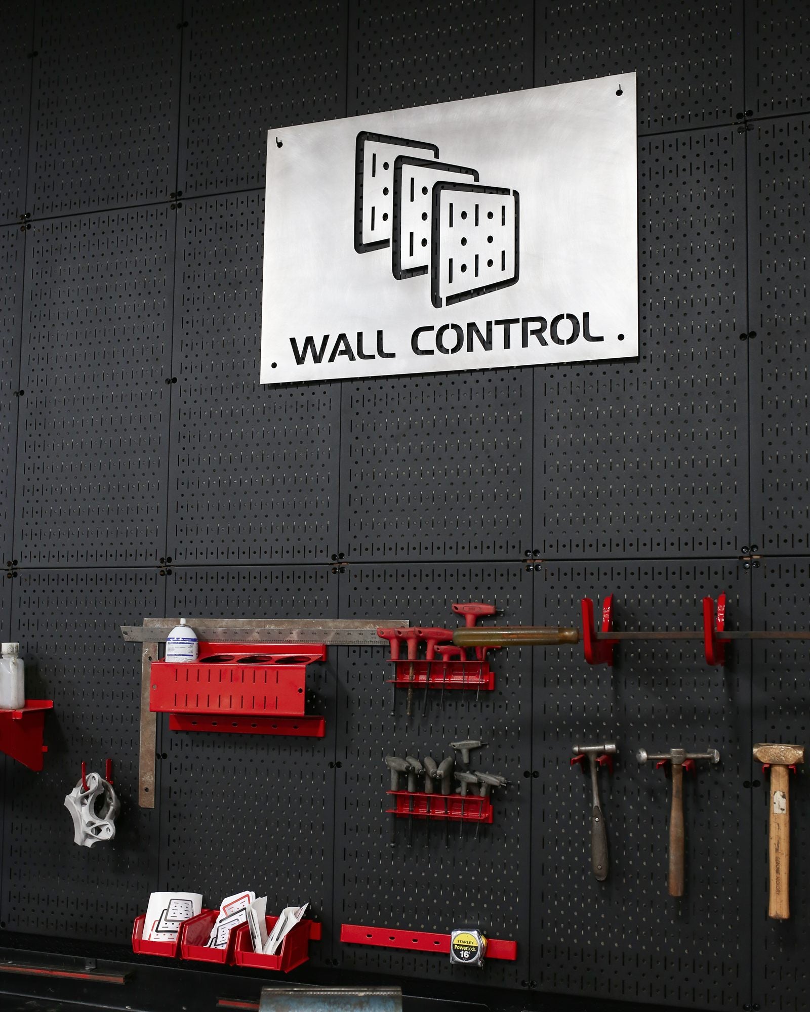 Wall Control metal pegboard wall with tools and Wall Control sign in a workshop