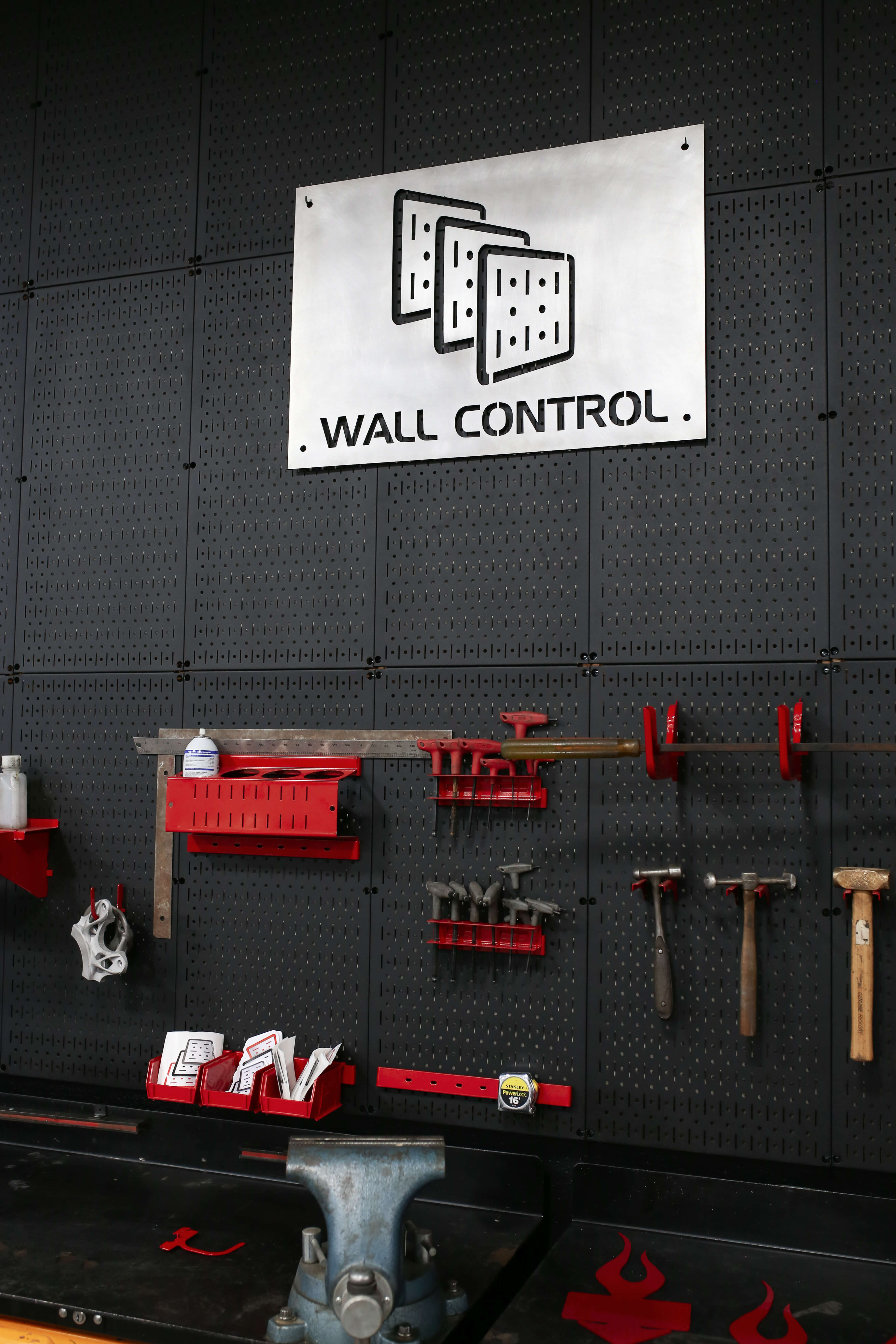 Wall control system with tools and equipment on a black pegboard wall.